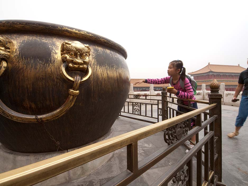 Girl Trying to Touch a Huge Bronze Cauldron in the Forbidden City, Beijing